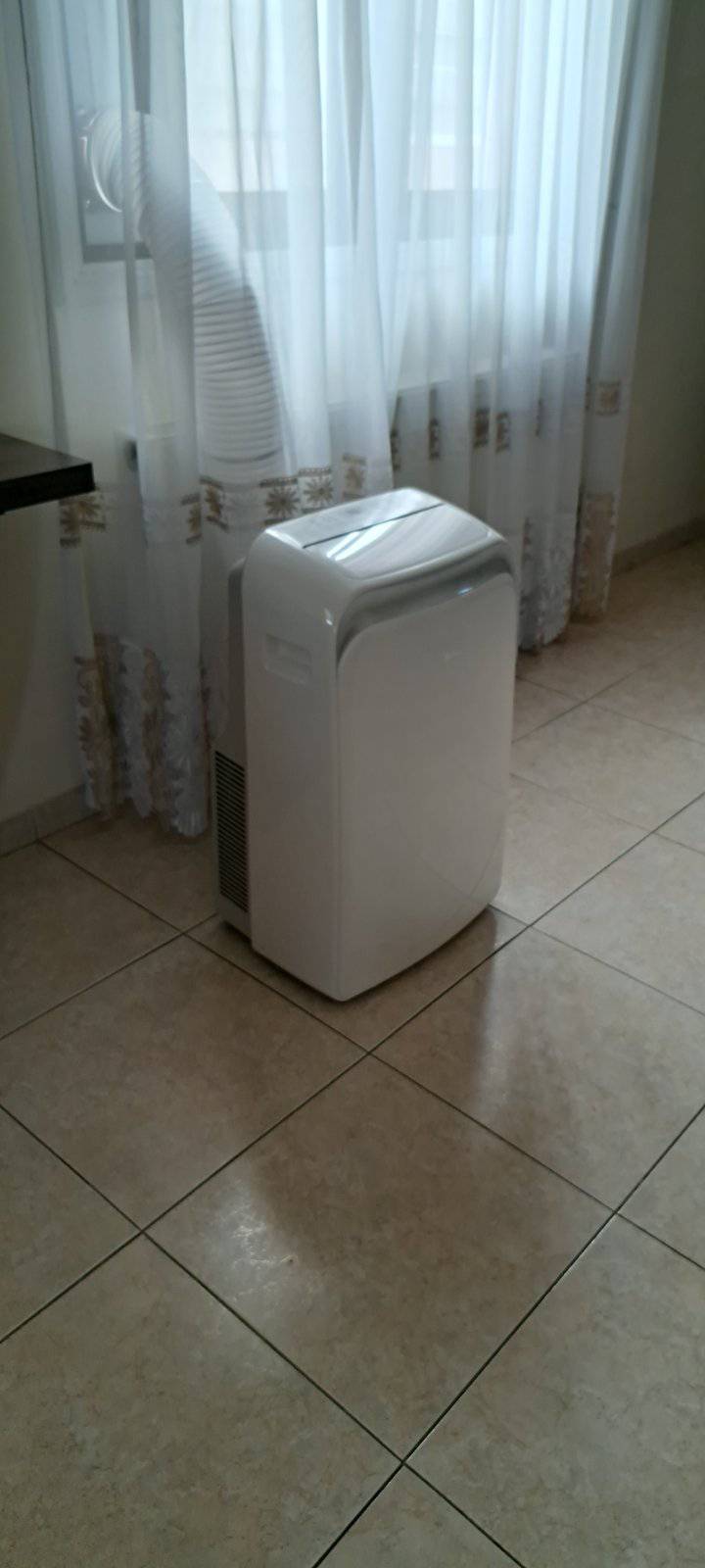 Portable AC unit next to window with exhaust hose
