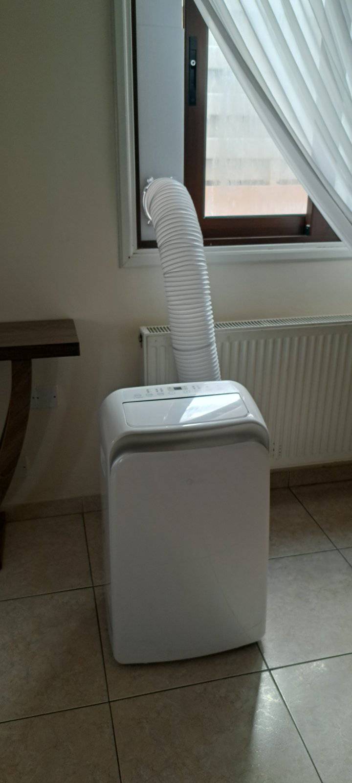 Portable AC unit with exhaust hose routed out the window